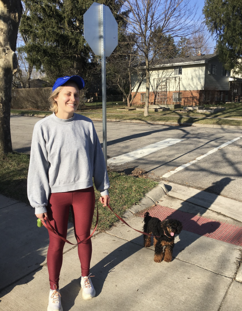 A woman smiling while on a walk with her dog