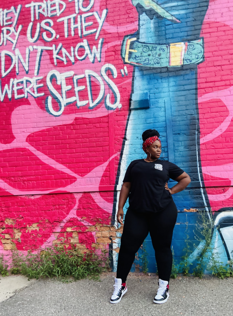 Woman posing in front of a colorful mural.